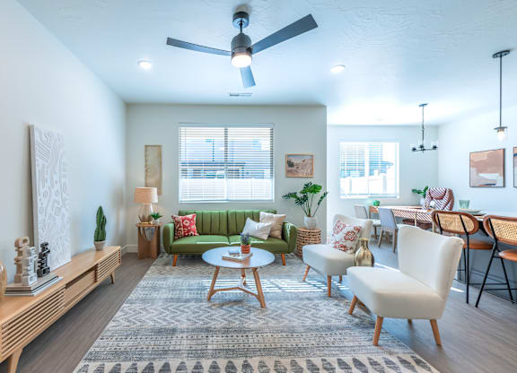 A living room with a green couch, a wooden table, and a ceiling fan.