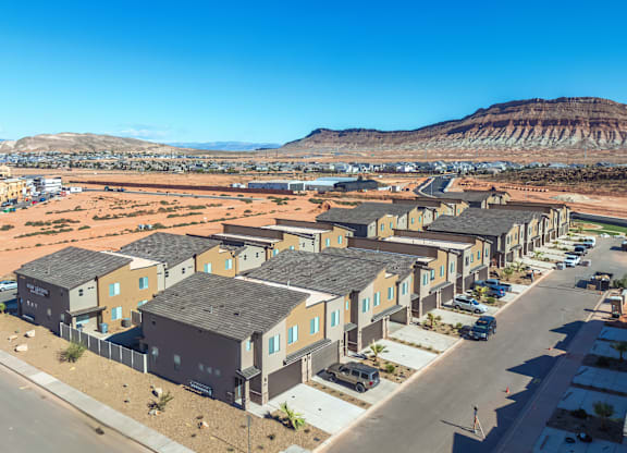 A row of houses in a desert-like area with mountains in the background.