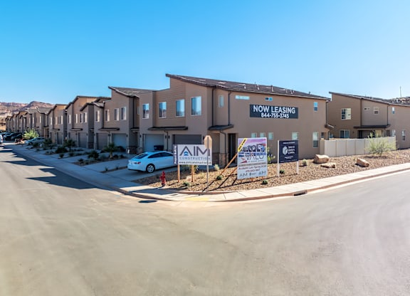 A row of houses with a sign that says "NOW LEASING" in front of them.