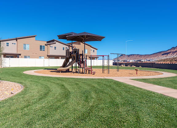 A playground with a slide and a swing set in a grassy area.