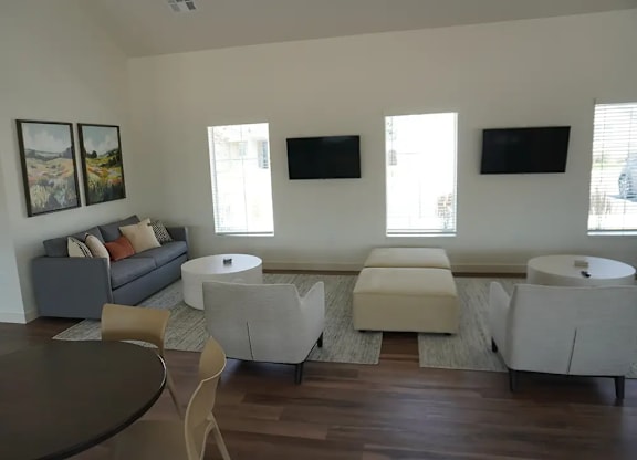 A living room with a grey couch, two chairs and a coffee table.