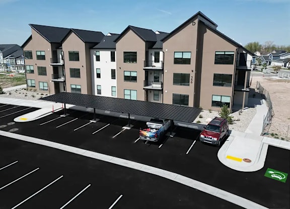 A parking lot in front of a building with a car parked in the spot with a sign on it.