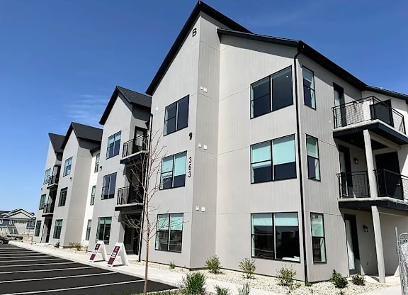 A modern apartment building with a parking lot in front.