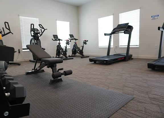A spacious gym with a variety of equipment including treadmills, stationary bikes, and dumbbells.