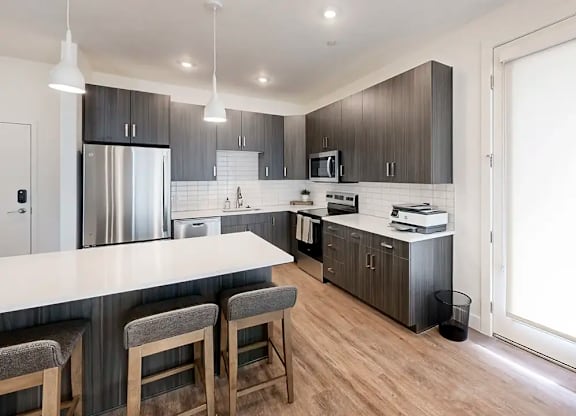 A modern kitchen with a bar area and stools.