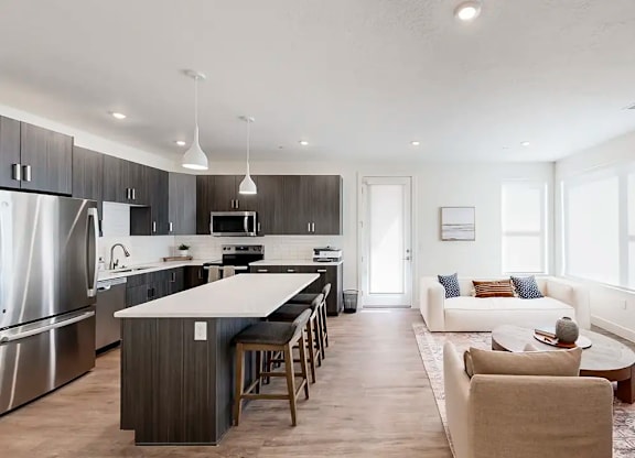 A modern kitchen with a large island and a living room with a couch.