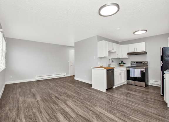 A kitchen with white cabinets and a wooden floor.