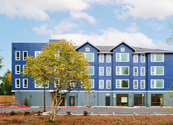 A blue building with a tree in front.