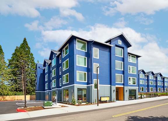 A blue building with a parking lot in front.