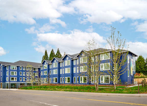 A large blue building with a parking lot in front.
