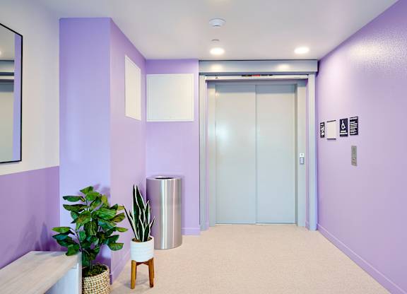 A hallway with a purple wall and a white bench.