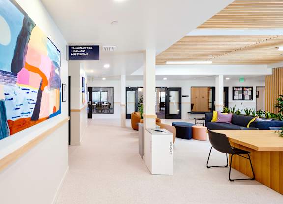 A modern office lobby with a large painting on the wall and a reception desk.