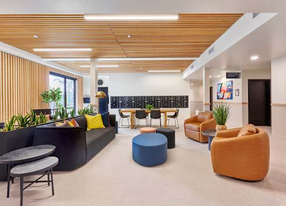 A modern office lounge with a variety of seating options and a plant.