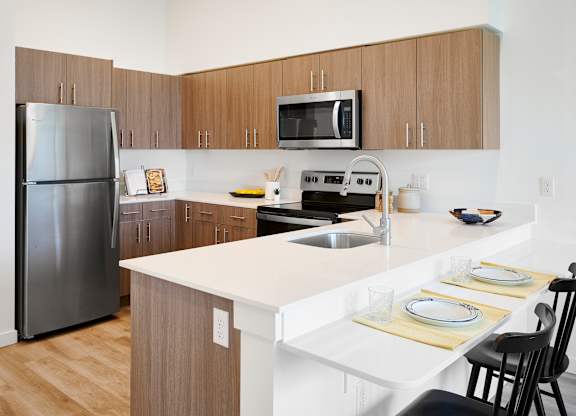A kitchen with a refrigerator, microwave, oven, and sink.