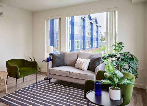 A living room with a couch, chair, and potted plant.