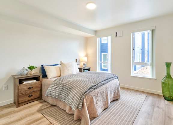 A bedroom with a bed, nightstand, and a green vase.