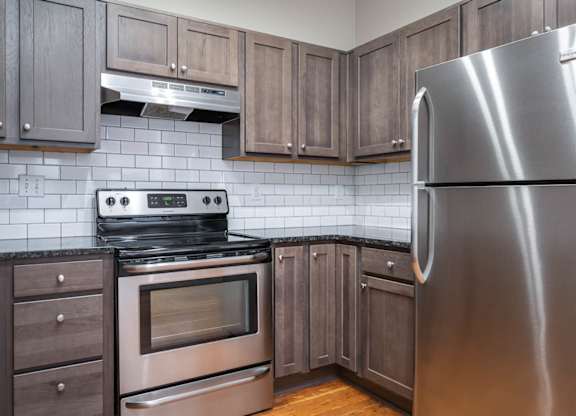 A modern kitchen with a stainless steel refrigerator, oven, and microwave.
