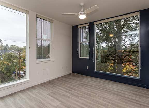 A room with a ceiling fan and sliding glass doors.