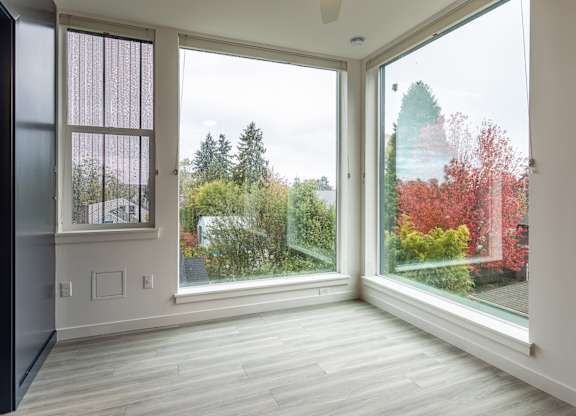 A room with a view of trees and a house through the windows.