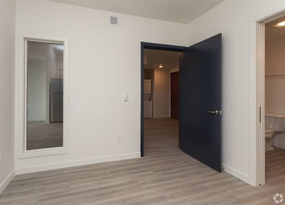 A room with a black door and a mirror on the wall.