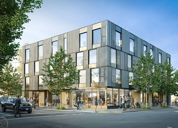 A modern building with a lot of windows and trees in front.