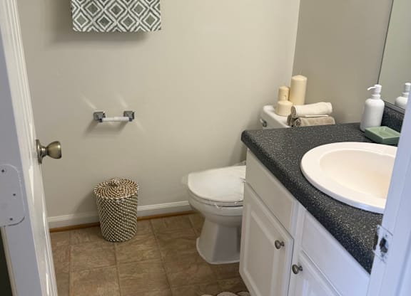 A bathroom with a toilet, sink, and trash can.
