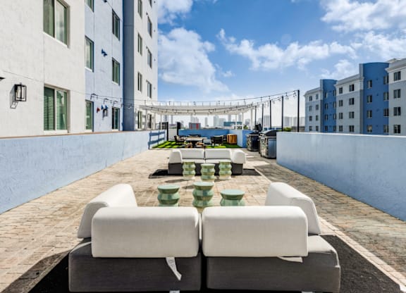 A patio with white couches and a table with green cups on it.