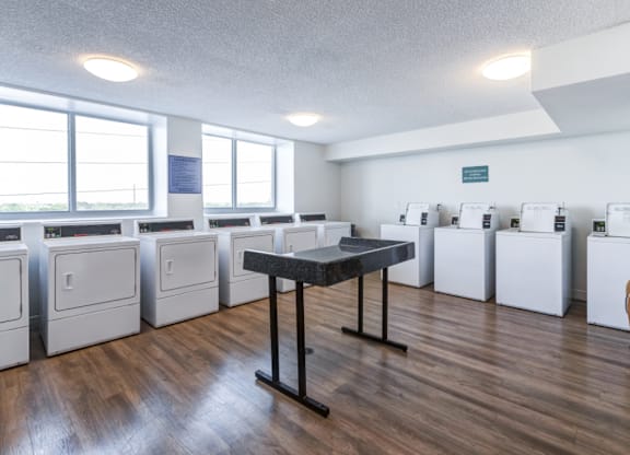A room with a table and washing machines.