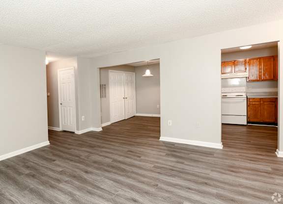 an empty living room and kitchen with white appliances and wood flooring at Avon Crossings, Durham, 27713
