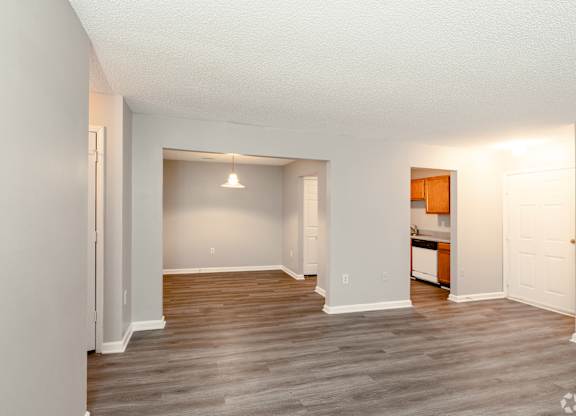 an empty living room with wood flooring and a kitchen at Avon Crossings, Durham North Carolina