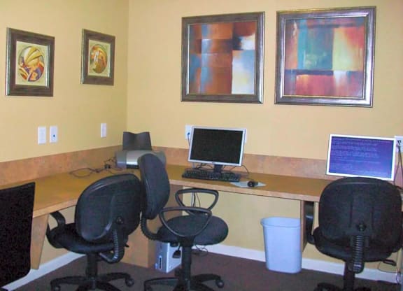 an office with a desk with a computer and chairs