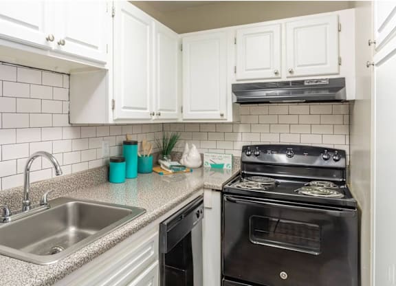 a kitchen with white cabinets and black appliances at Bradley Square, South Carolina