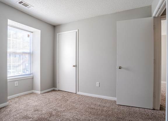 A room with a carpeted floor and two white doors.at Brookside Pointe Apartments, Travelers Rest, SC 29690