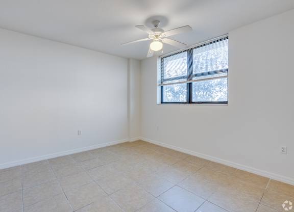 Empty room with a ceiling fan and a window.