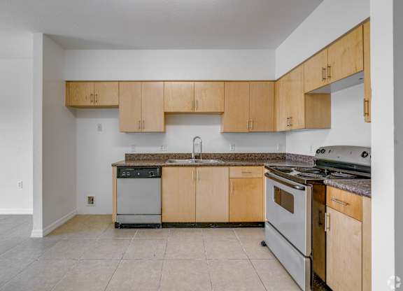 A kitchen with wooden cabinets and a stainless steel dishwasher.