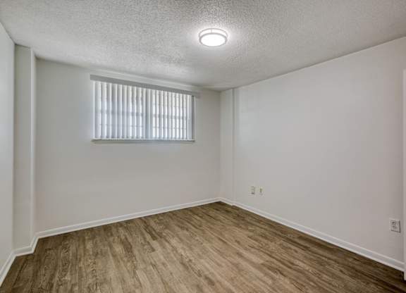 a bedroom with white walls and a window