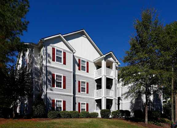 a gray apartment building with red shutters and a blue sky in the background at Avon Crossings, Durham, NC  