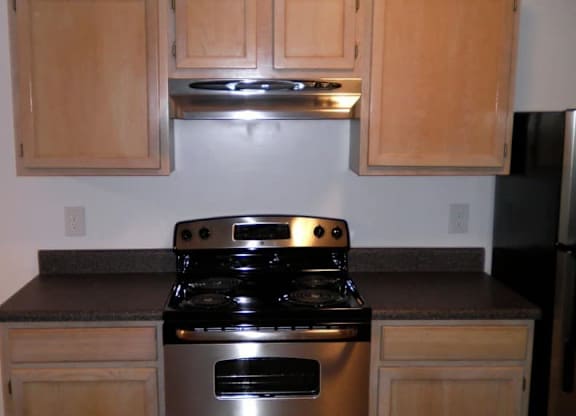 A black stove top oven with a silver range hood above it.