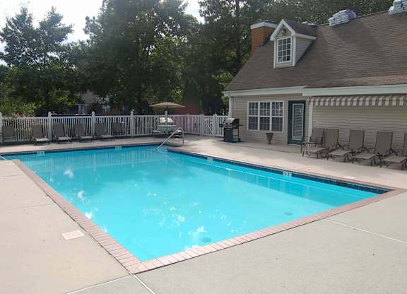 A small residential pool with a deck and a house in the background.