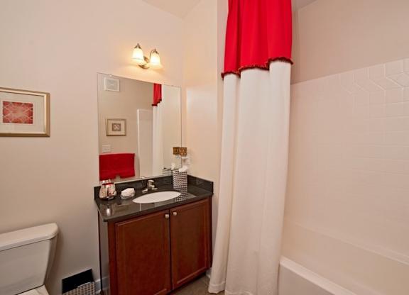 A bathroom with a white tub and a red shower curtain.