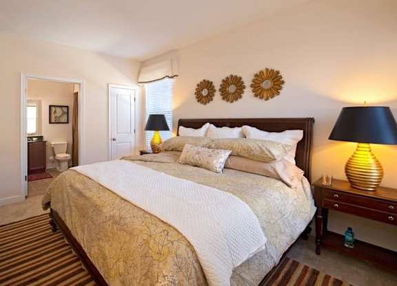 A bedroom with a large bed and a lamp on the side table.