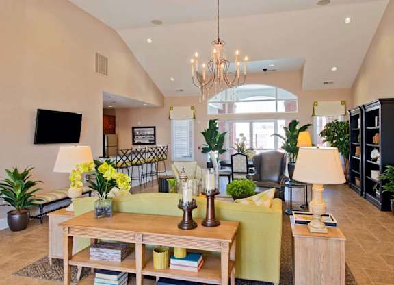 A well-lit living room with a large chandelier and a green sofa.