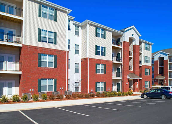 A row of apartment buildings with a car parked in the parking lot.