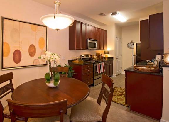 A kitchen with a table and chairs in the foreground and a framed artwork on the wall.