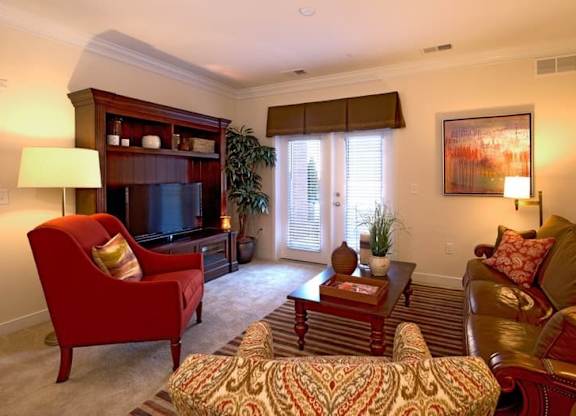 A living room with a red chair and a brown couch.