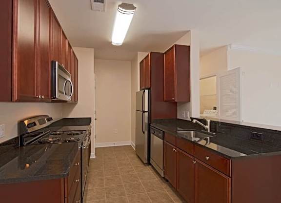 A kitchen with brown cabinets and black countertops.