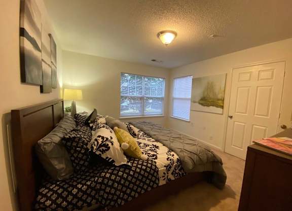 A bedroom with a bed, nightstand, and window.