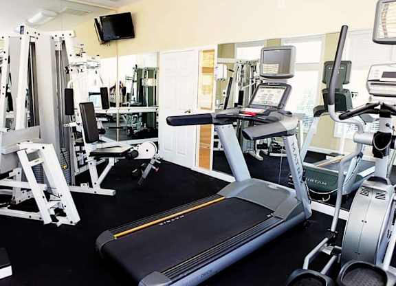 A gym with a treadmill, weights, and exercise machines.