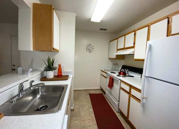 A kitchen with white cabinets and a white fridge.