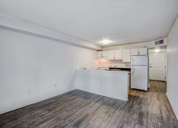 a kitchen and living room with white walls and wood flooring